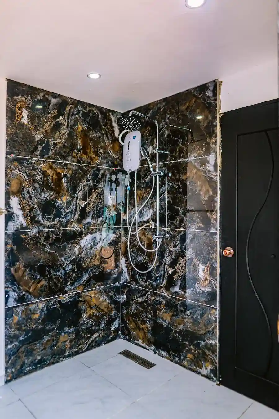Modern corner shower featuring dark marble-patterned tiles inside the Family Room at Turtle Seaweed Resort.